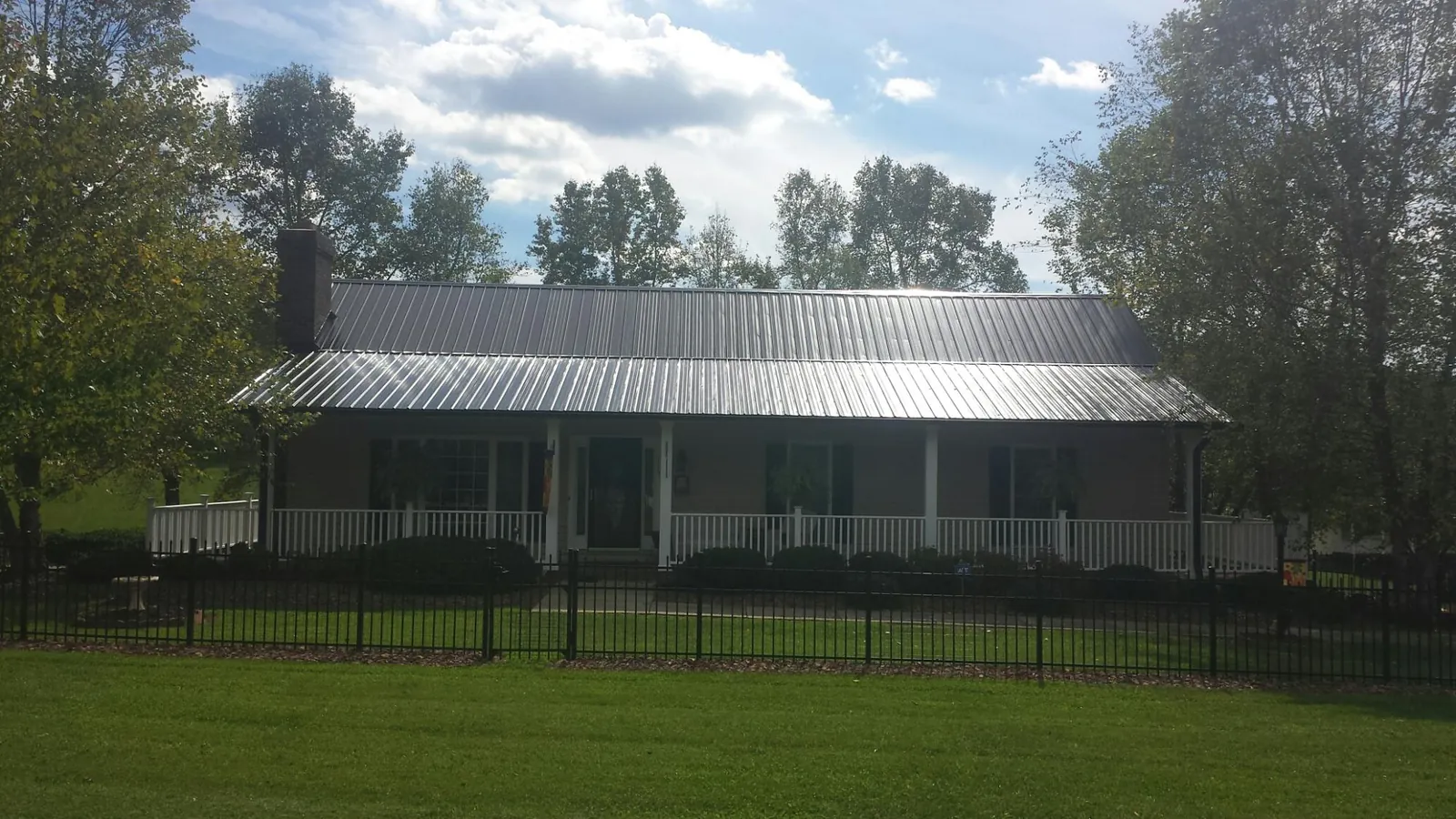 Gray metal roof on a brick ranch with a full width front porch — Gutter Guard Installation work by our crew in Kemmerer