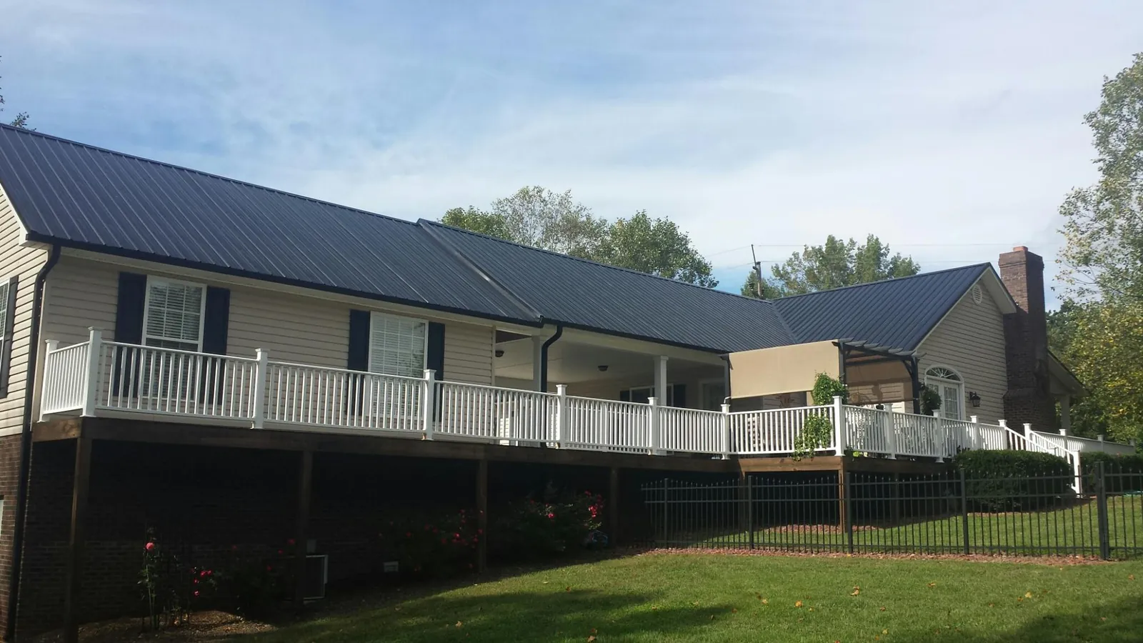Black metal roof above a long white railed deck on a hillside home in Kemmerer