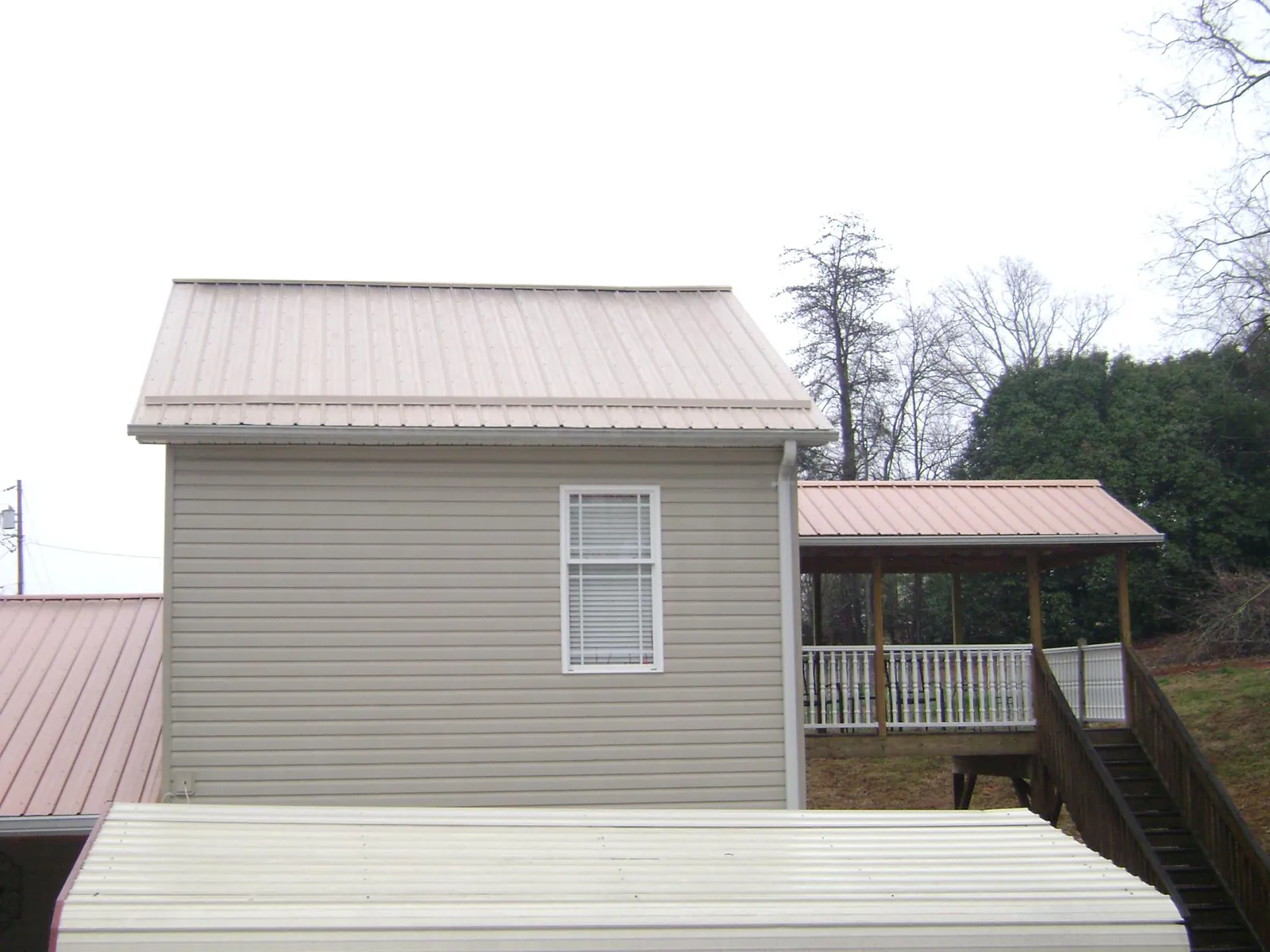 Tan metal roofs on a two story addition and attached porch, from a Roof Replacement job in Kemmerer