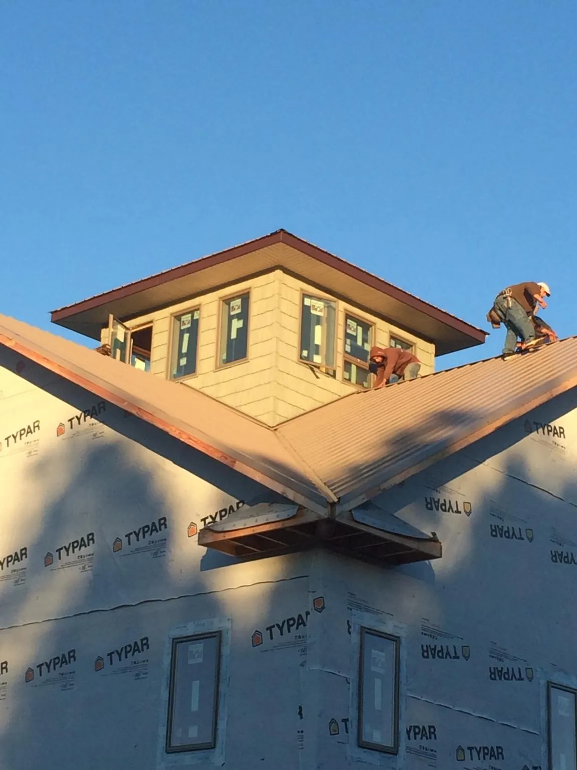 Roofers working around a rooftop cupola on a new metal roof at sunset — Roof Waterproofing in Kemmerer by Roofing Brothers